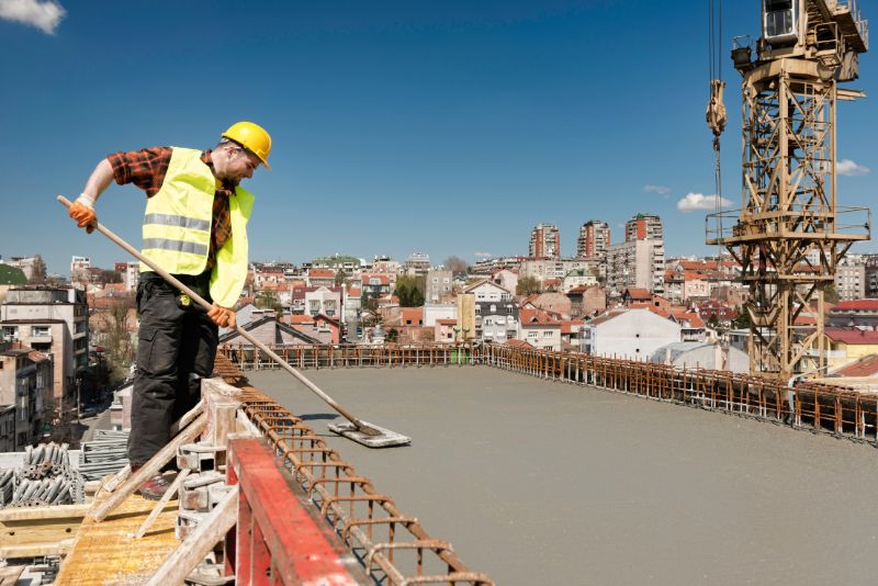 builder smoothong concrete surface on top of a tall building